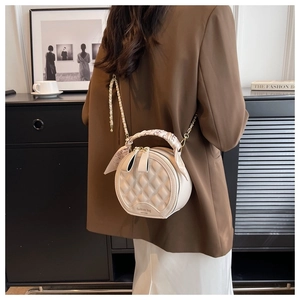 Détail du sac à main rond matelassé beige avec poignée en foulard de soie et chaîne