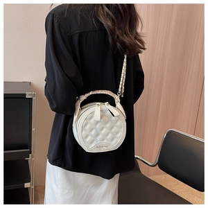 Détail d'un sac à main rond blanc matelassé avec poignée en foulard et bandoulière