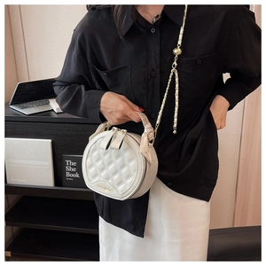 Détail du sac rond blanc matelassé avec chaîne dorée et foulard en soie décoratif