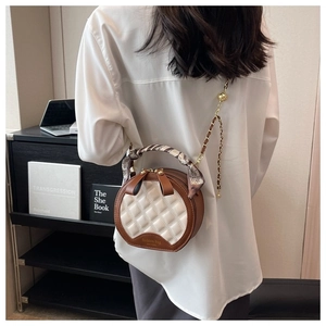 Détail du sac rond en cuir matelassé avec bandoulière chaîne et poignée foulard