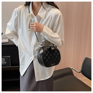 Détail d'un sac rond en cuir matelassé avec poignée foulard et bandoulière dorée