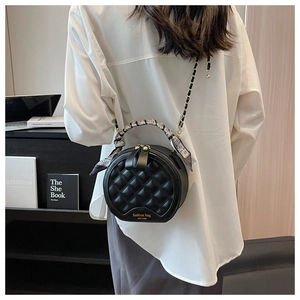Détail du sac rond en cuir matelassé avec chaîne dorée et poignée en foulard