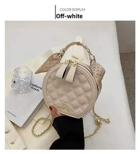 Détail du sac à main rond matelassé crème avec poignée foulard et chaîne dorée