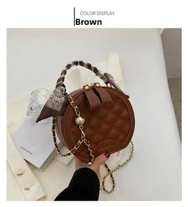 Détails d'un sac à main rond matelassé marron avec chaîne dorée et poignée en foulard