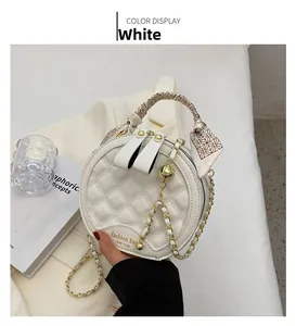 Détail d'un sac rond blanc matelassé avec poignée en soie et pendentif doré chic