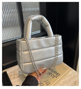 Detail of silver quilted puffer handbag with metallic finish and beaded chain strap