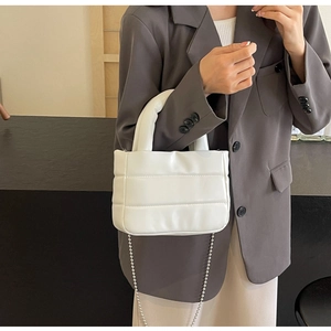 Detailed shot of white quilted puffy bucket bag with silver chain strap on a model