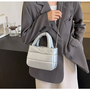 Close-up of quilted silver puffer bag with metallic finish and round ball chain strap