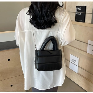 Close-up of black quilted bucket bag with pearl chain strap and leather luster finish