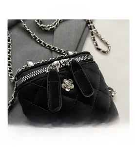 Close-up of black quilted mini bag featuring silver camellia clasp and chain strap