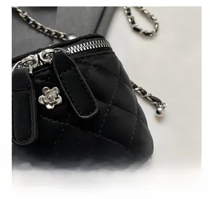 Detail of black quilted crossbody bag with silver flower hardware and chain strap