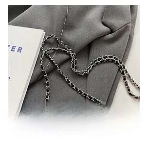 Detail of silver metal chain strap and quilted leather texture on black handbag