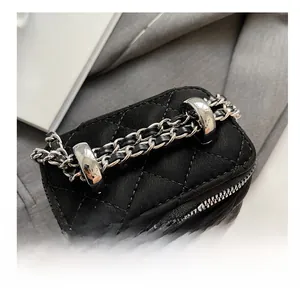 Macro shot of silver metal chain strap and quilted leather texture on black handbag