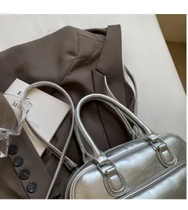 Detail of silver metallic textured handbag with cracked finish on brown suit background
