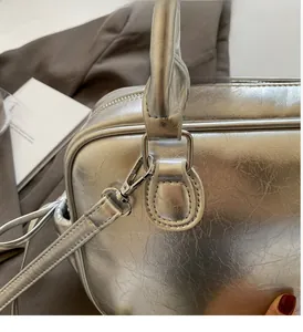 Detailed view of shiny silver backpack with pleated metallic texture and chrome ring hardware