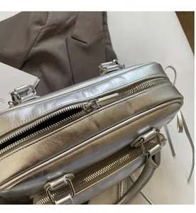 Close-up of the smooth dual metal zippers and crinkled silver texture on this handbag
