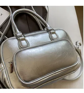 Detail of silver metallic Boston bag showing shiny texture and front zipper pocket