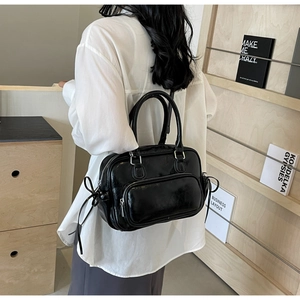 Close-up of black glossy PU leather backpack with side bow ties and dual handles