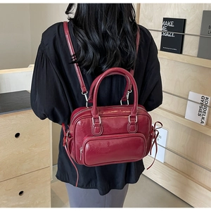 Detail of burgundy PU leather backpack showing glossy finish and silver metal zippers