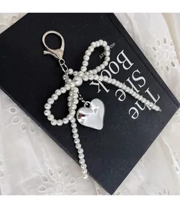 Detailed view of elegant pearl bow charm with a silver heart pendant on a bag handle