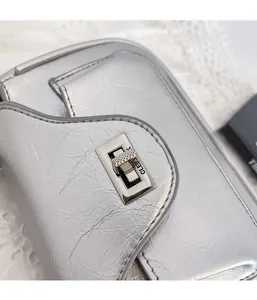 Detail of silver crinkled PU leather handbag featuring a rectangular metal twist lock