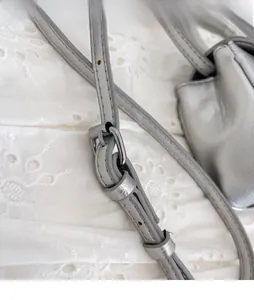 Detail of silver-grey leather bag featuring an adjustable shoulder strap and metal buckle