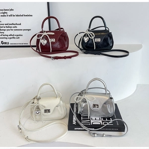 Detail of mini PU leather crossbody bags with pearl bows and silver heart charms in four colors
