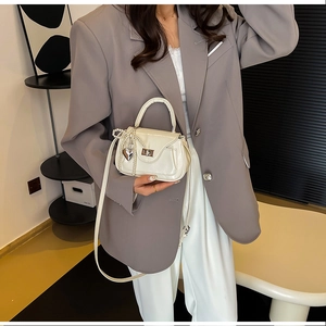 Close-up of cream PU leather crossbody bag with silver twist lock and pearl bow detail