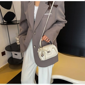 Detail of cream white handbag with pearl bow charm and silver heart pendant detail
