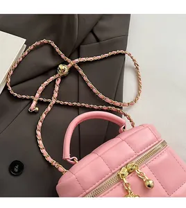 Détail du sac matelassé rose montrant la chaîne dorée avec boule de réglage iconique