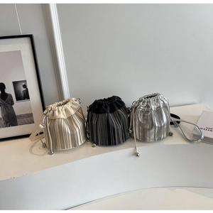 Drei trendige Quasten-Eimertaschen in Creme, Schwarz und Silber auf minimalistischem Display