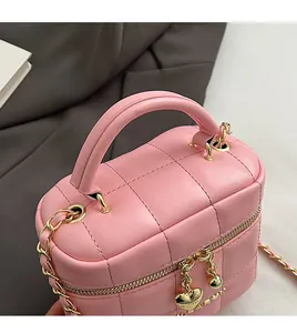 Détail d'un sac rose matelassé avec fermeture éclair dorée et pendentif en forme de cœur