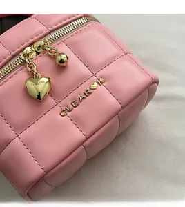 Détail du sac seau matelassé rose avec fermetures éclair en cœur doré et logo CLEAR métal