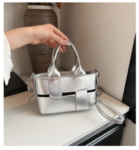 Close-up of a silver woven bucket bag with metallic luster and adjustable strap