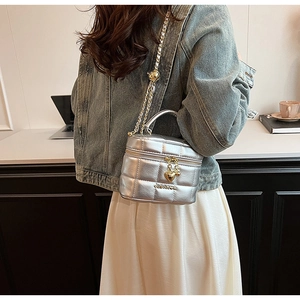 Détail du sac seau matelassé argenté avec chaîne dorée et breloque cœur