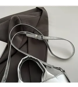 Detail of silver handbag featuring an adjustable slim shoulder strap and metal buckle