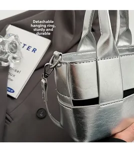 Close-up of metallic silver woven bucket bag featuring detachable shoulder strap and lobster clasp