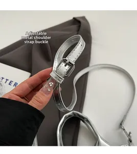 Detail of adjustable silver metallic strap with polished buckle on a stylish handbag