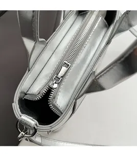 Detail of a silver woven bucket bag featuring a smooth metal zipper and detachable strap