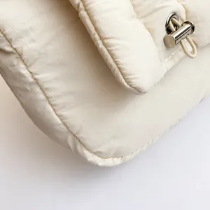 Detail van de witte gewatteerde stof met een glanzende zilveren metalen sluiting