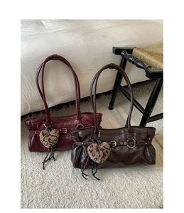 Detailed view of glossy patent leather tote bags with buckles and leopard heart charms