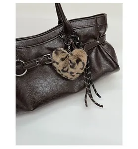 Détail d'un sac cabas marron foncé avec texture grainée, cœur léopard et boucle métal