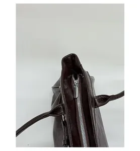 Détail d'un sac en cuir ciré marron foncé montrant la fermeture éclair en métal argenté