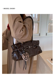 Détail du cabas marron foncé en cuir brillant avec boucle argentée et breloque léopard