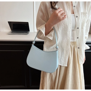 Light blue crescent shoulder bag shown in an office setting with a minimal design