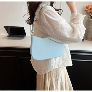 Pale blue faux leather hobo bag worn by a model in a minimal office setting