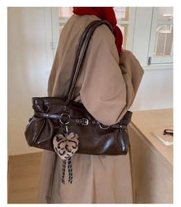 Detail of dark brown leather tote bag with buckle and leopard heart plush charm