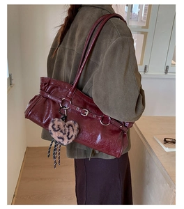Detail of burgundy leather tote bag with metallic buckle and leopard heart plush charm