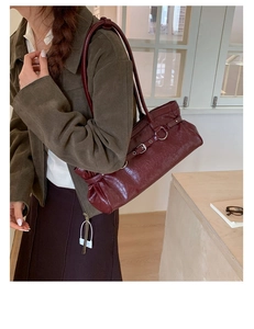 Close-up of a burgundy leather tote bag with silver buckle and adjustable shoulder strap