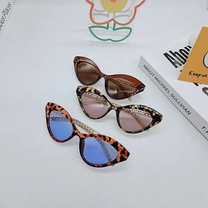 Detail of cat eye sunglasses with gold chain temples and leopard print resin frames